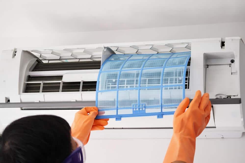 A man replaces the air conditioner's filter