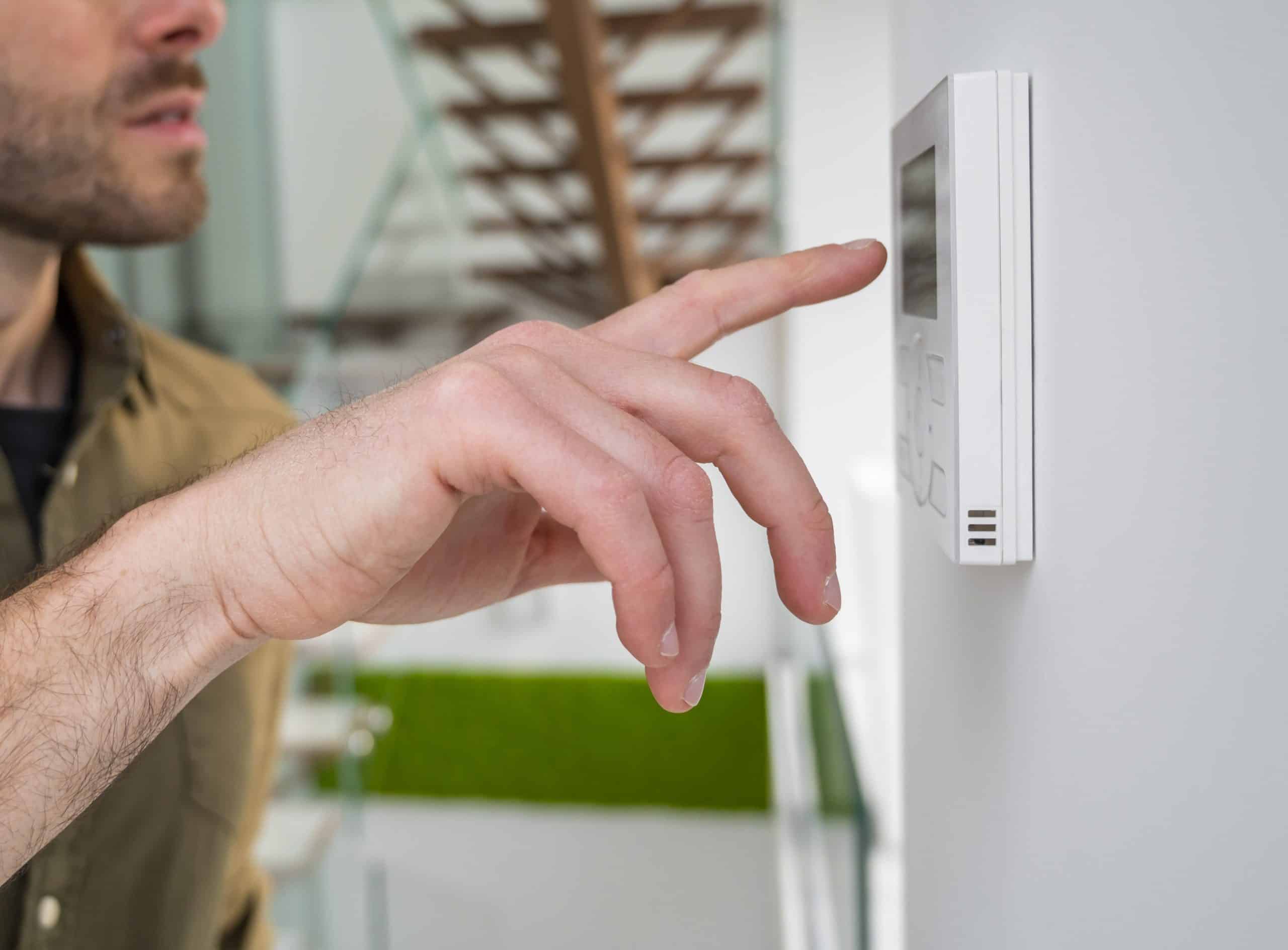 homeowner adjusting smart thermostat air conditioning