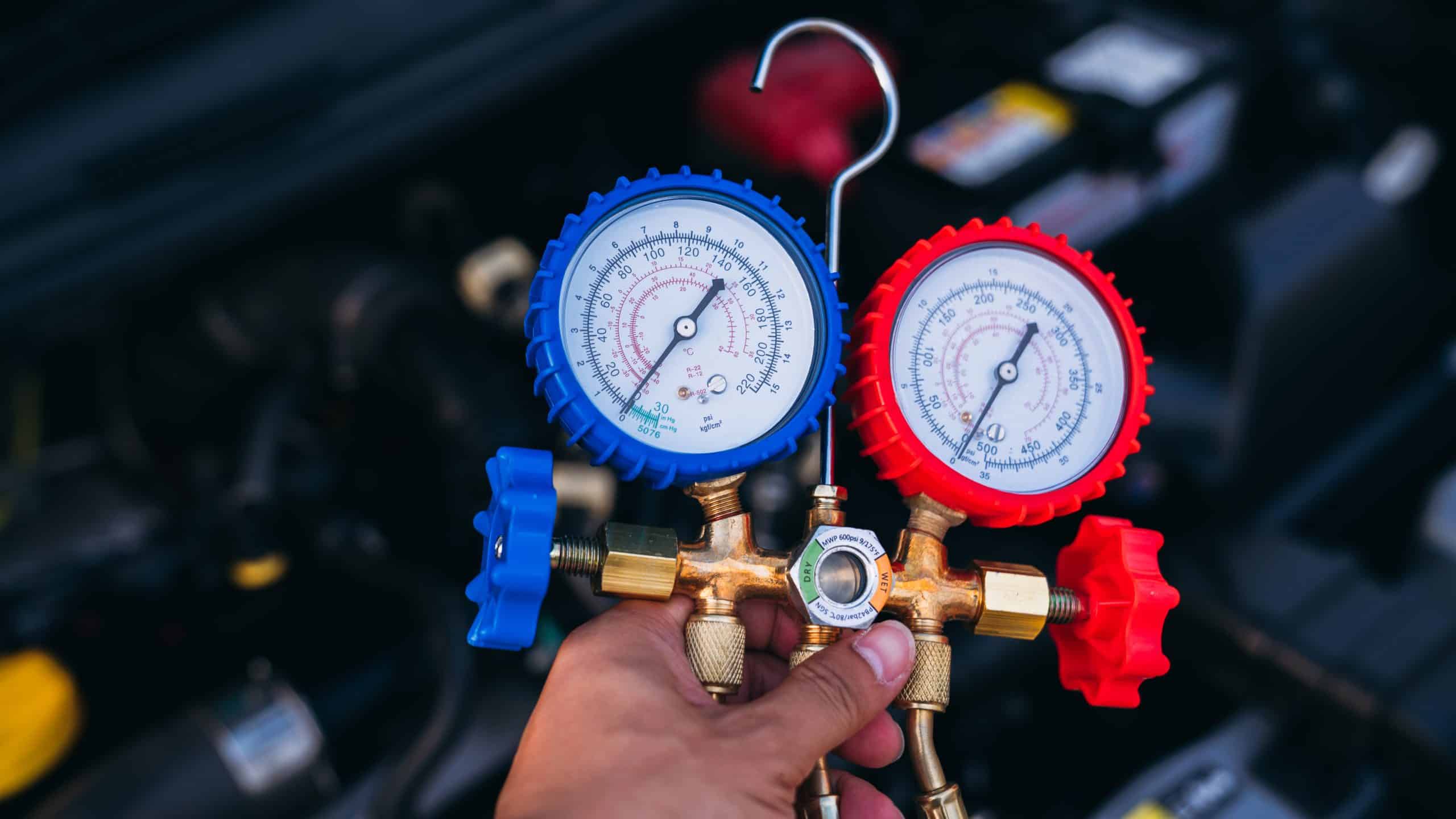 technician checking refrigerant pressure AC system