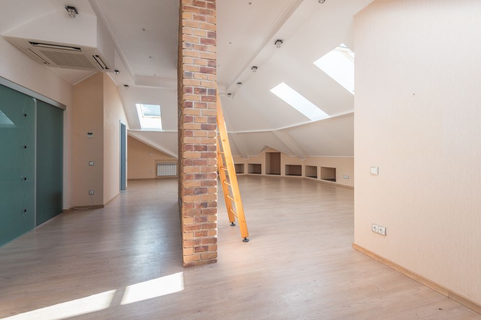 Bright empty attic room with sloped ceiling and skylights, the kind of space air handlers are installed in