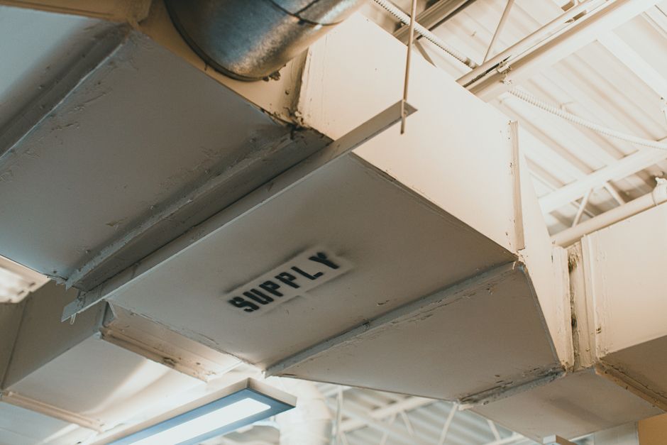 Metal supply ductwork running below a ceiling, with the word SUPPLY stencilled on the side