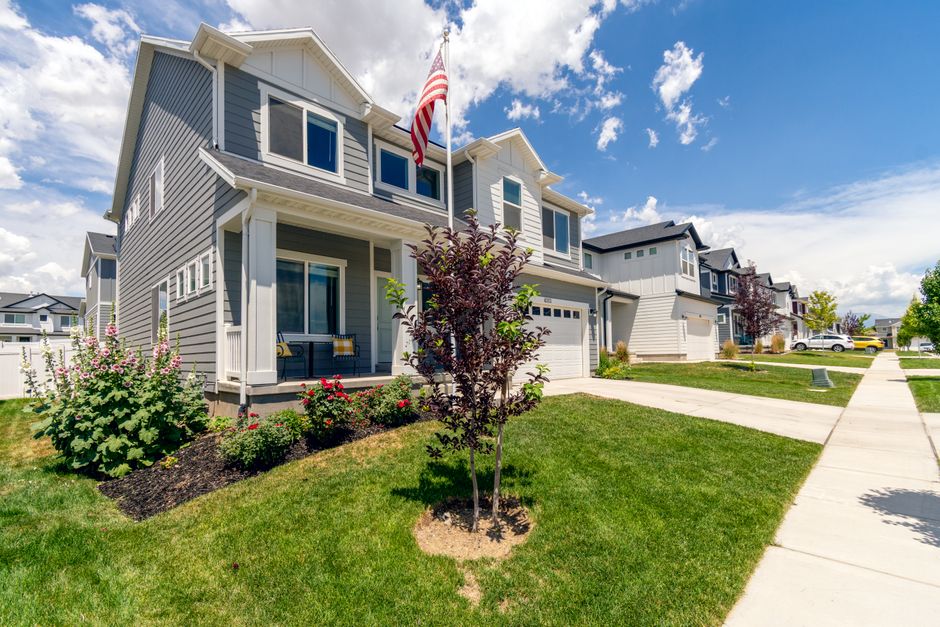 Residential street of two storey homes with front lawns and a flag on a clear sunny day