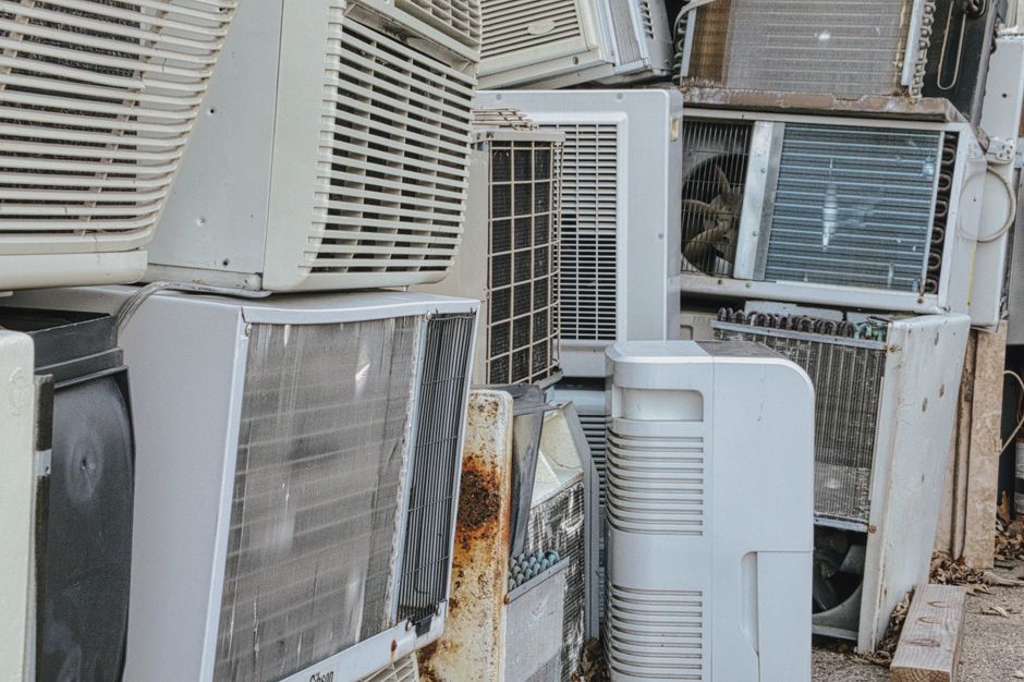 Stack of old and disused air conditioning units showing rust and worn casings