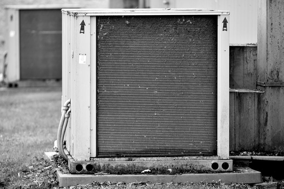 Outdoor HVAC unit photographed side on, showing the full height of its condenser coil