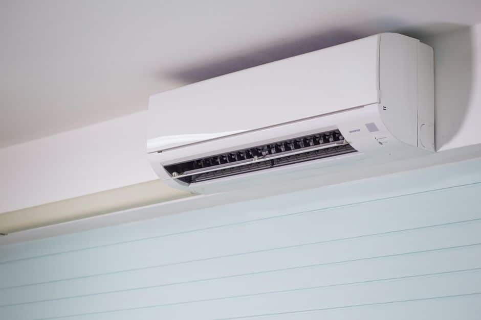 White wall mounted indoor heating and cooling unit fitted high on an interior wall